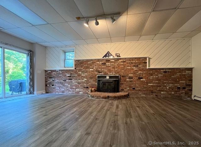 47 Merwin Brook Rd, Brookfield, CT 06804 - unfurnished living room with brick wall, rail lighting, wood finished floors, a wood stove, and a drop ceiling