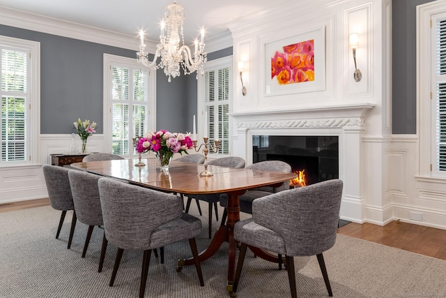354 S Ave, New Canaan, CT 06840 - dining space featuring wood finished floors, a chandelier, a high end fireplace, wainscoting, and a decorative wall