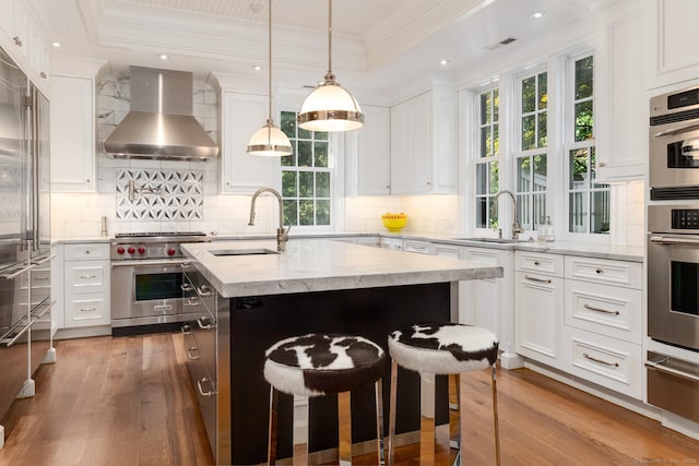 354 S Ave, New Canaan, CT 06840 - kitchen featuring wall chimney exhaust hood, high quality appliances, a warming drawer, ornamental molding, and wood finished floors