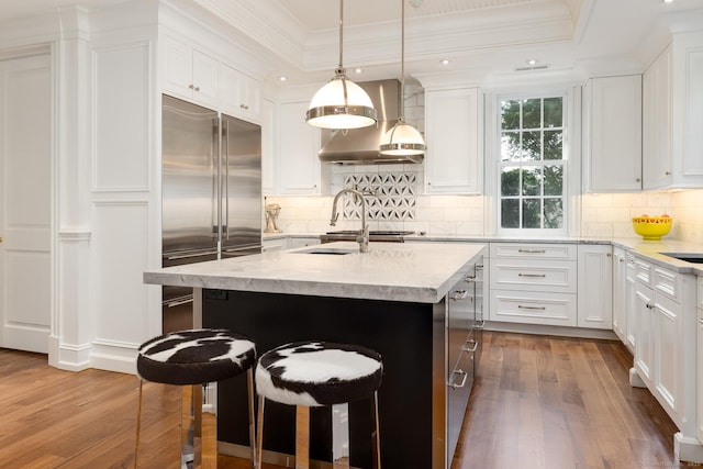 354 S Ave, New Canaan, CT 06840 - kitchen featuring wall chimney range hood, dark wood-style floors, built in fridge, white cabinets, and a tray ceiling