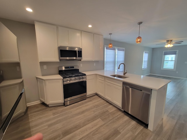 87 Fairview Ave, West Haven, CT 06516 - kitchen with stainless steel appliances, light countertops, a peninsula, light wood finished floors, and white cabinetry