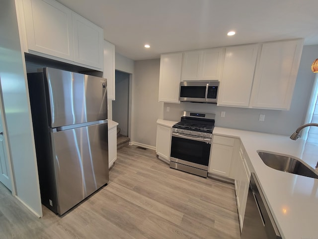 87 Fairview Ave, West Haven, CT 06516 - kitchen featuring appliances with stainless steel finishes, white cabinetry, light wood-style flooring, light countertops, and recessed lighting