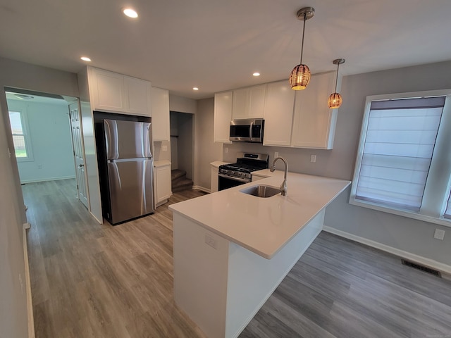 87 Fairview Ave, West Haven, CT 06516 - kitchen with appliances with stainless steel finishes, white cabinets, light countertops, light wood-type flooring, and a peninsula