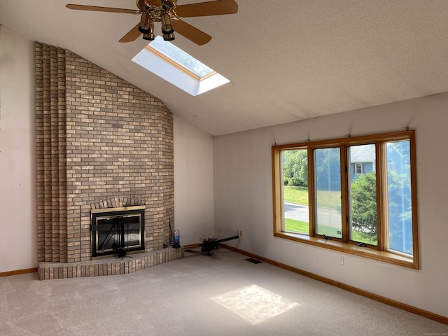 127 Nicole Dr, Milford, CT 06460 - unfurnished living room with a ceiling fan, vaulted ceiling, carpet flooring, a fireplace, and a skylight