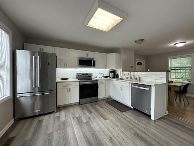 39 Ames Ave Unit A, Meriden, CT 06451 - kitchen featuring appliances with stainless steel finishes, light wood-type flooring, backsplash, and a peninsula
