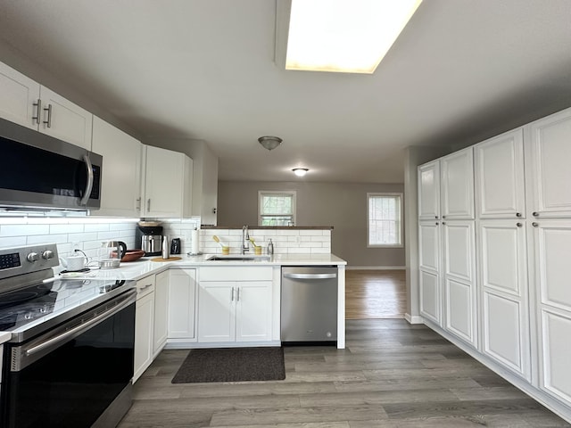 39 Ames Ave Unit A, Meriden, CT 06451 - kitchen with appliances with stainless steel finishes, a peninsula, decorative backsplash, and white cabinetry