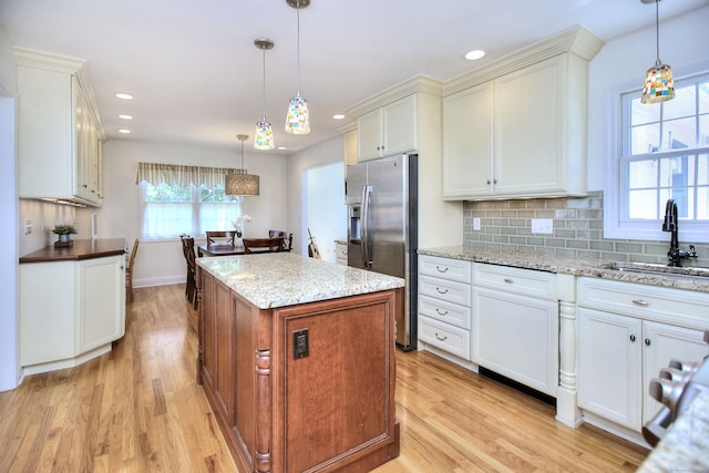 1221 Merritt St, Fairfield, CT 06825 - kitchen featuring stainless steel fridge with ice dispenser, light wood-type flooring, a kitchen island, decorative backsplash, and recessed lighting