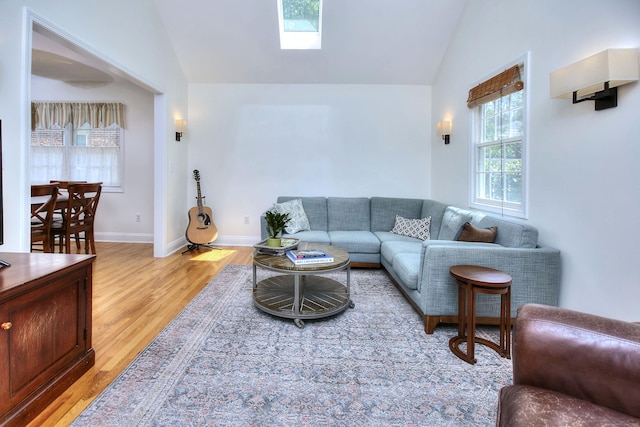 1221 Merritt St, Fairfield, CT 06825 - living room featuring plenty of natural light, light wood finished floors, a skylight, and high vaulted ceiling