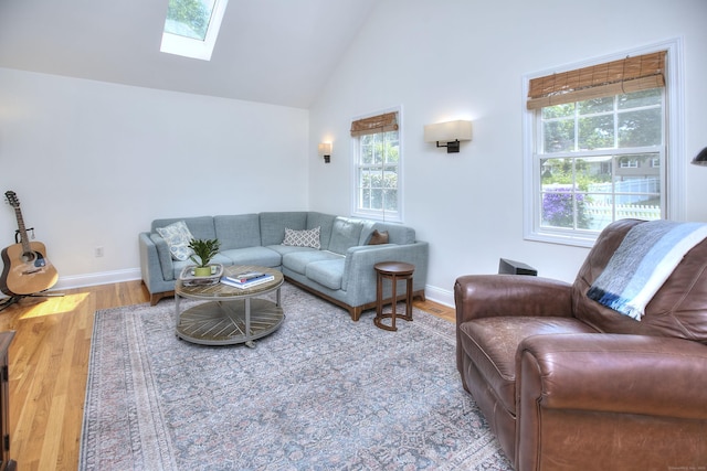 1221 Merritt St, Fairfield, CT 06825 - living room featuring healthy amount of natural light, a skylight, high vaulted ceiling, and wood finished floors