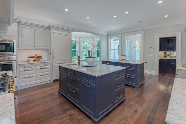 14 Market St, Ridgefield, CT 06877 - kitchen featuring an island with sink, appliances with stainless steel finishes, dark wood-style flooring, decorative backsplash, and ornamental molding