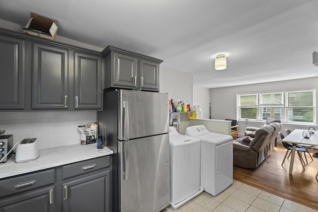 212 Sheffield Ave, New Haven, CT 06511 - kitchen featuring freestanding refrigerator, washing machine and dryer, light tile patterned floors, gray cabinetry, and backsplash