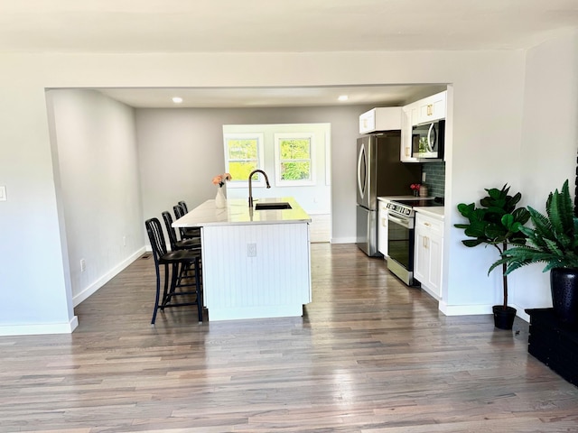 26 Nejako Dr, Middletown, CT 06457 - kitchen with appliances with stainless steel finishes, a breakfast bar area, white cabinetry, a kitchen island with sink, and dark wood-type flooring