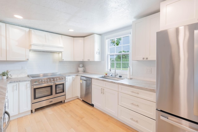 282 Montgomery Rd, Westfield, MA 01085 - kitchen featuring appliances with stainless steel finishes, custom exhaust hood, light wood-style flooring, white cabinetry, and backsplash