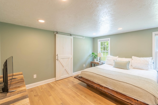 282 Montgomery Rd, Westfield, MA 01085 - bedroom featuring a barn door, light wood finished floors, recessed lighting, and a textured ceiling