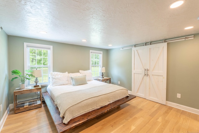 282 Montgomery Rd, Westfield, MA 01085 - bedroom with light wood-style floors, a barn door, a textured ceiling, multiple windows, and recessed lighting