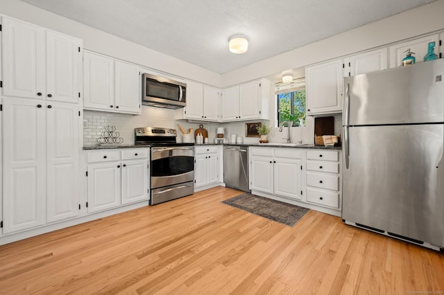 578 Pilgrim Hbr Unit 578, Wallingford, CT 06492 - kitchen featuring stainless steel appliances, dark countertops, light wood-type flooring, white cabinetry, and a textured ceiling