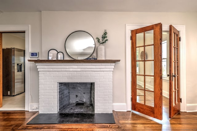21 Orange Ter, West Haven, CT 06516 - detailed view of stainless steel refrigerator with ice dispenser, wood finished floors, and a brick fireplace
