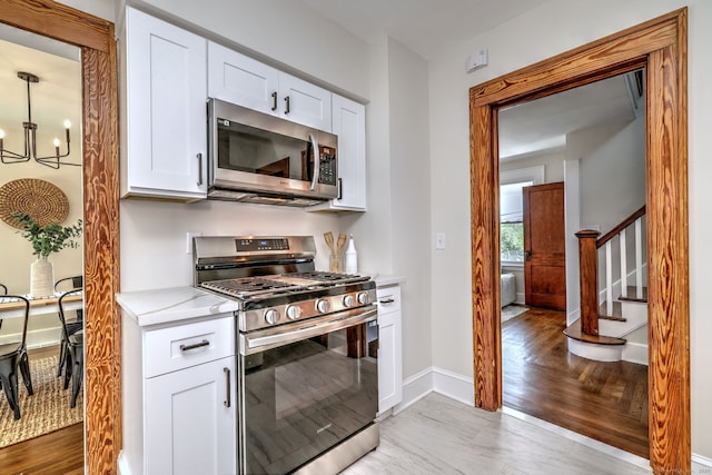 21 Orange Ter, West Haven, CT 06516 - kitchen featuring appliances with stainless steel finishes, a chandelier, white cabinets, and light wood-style flooring