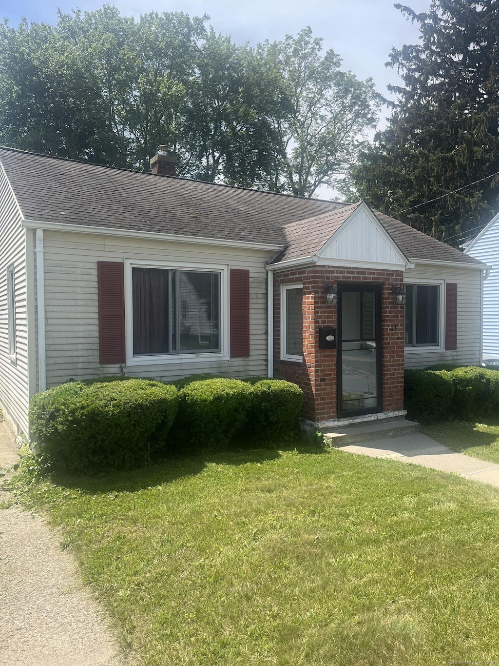 31 Byrneside Ave, Waterbury, CT 06704 - view of front facade featuring a front lawn, a chimney, brick siding, and roof with shingles