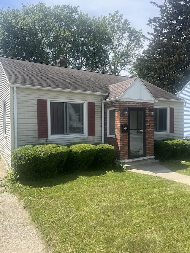 31 Byrneside Ave, Waterbury, CT 06704 - view of front facade featuring a front lawn, a chimney, brick siding, and roof with shingles