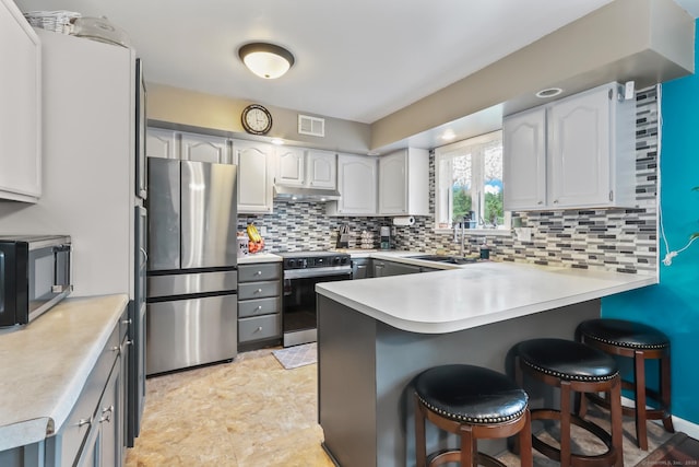 7 Pheasant Run Rd Unit 1, Kent, CT 06757 - kitchen featuring stainless steel appliances, a peninsula, under cabinet range hood, tasteful backsplash, and a kitchen bar