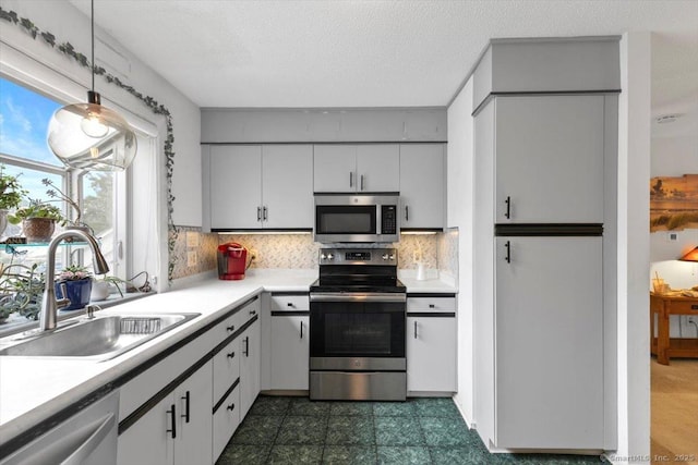 93 Cosey Beach Ave Apt 5, East Haven, CT 06512 - kitchen with appliances with stainless steel finishes, light countertops, decorative backsplash, pendant lighting, and white cabinets