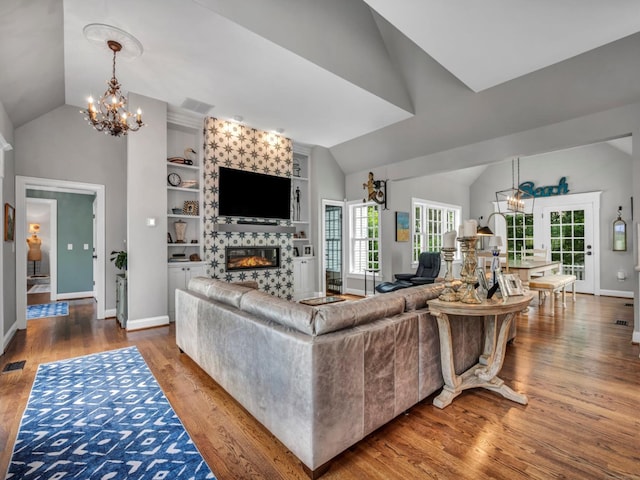 14 Ely Ln, Killingworth, CT 06419 - living area featuring vaulted ceiling, a chandelier, a large fireplace, wood finished floors, and built in features