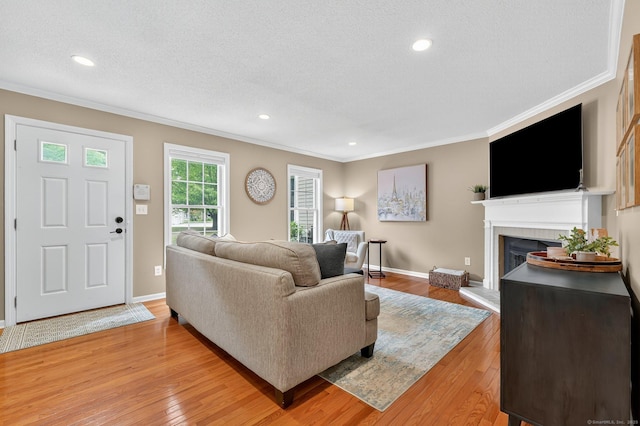 215 Georgetown Dr, Glastonbury, CT 06033 - living area with crown molding, light wood-style flooring, a tiled fireplace, recessed lighting, and a textured ceiling