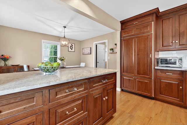 215 Georgetown Dr, Glastonbury, CT 06033 - kitchen with light wood-type flooring, light stone countertops, decorative light fixtures, backsplash, and a chandelier