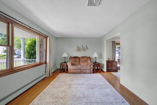 288 Pine Ln, Wethersfield, CT 06109 - living room with a baseboard heating unit, plenty of natural light, wood finished floors, and a textured ceiling