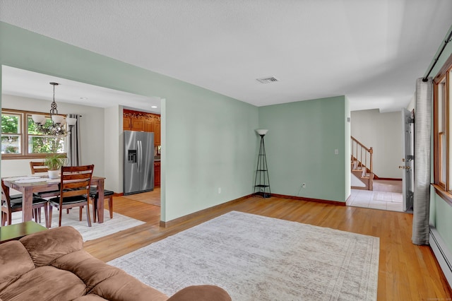 288 Pine Ln, Wethersfield, CT 06109 - living room with stairway, light wood-style flooring, a chandelier, and a baseboard radiator
