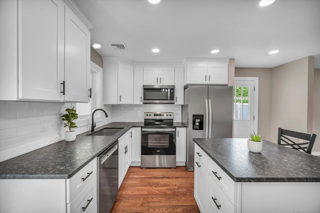 2 Riverview Pl, Cromwell, CT 06416 - kitchen featuring appliances with stainless steel finishes, white cabinetry, a kitchen island, decorative backsplash, and recessed lighting