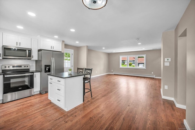 2 Riverview Pl, Cromwell, CT 06416 - kitchen featuring appliances with stainless steel finishes, baseboard heating, a kitchen bar, dark countertops, and healthy amount of natural light