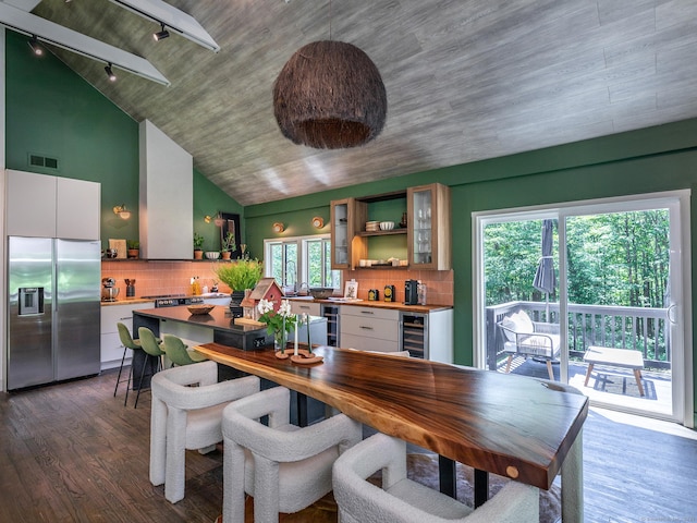 40 Revere Rd, Washington, CT 06793 - dining area with track lighting, wine cooler, vaulted ceiling, dark wood-type flooring, and a bar