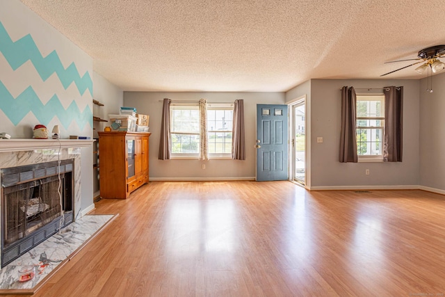 286 Laura Blvd Unit 286, Norwich, CT 06360 - unfurnished living room with a textured ceiling, a fireplace, ceiling fan, wood finished floors, and an accent wall