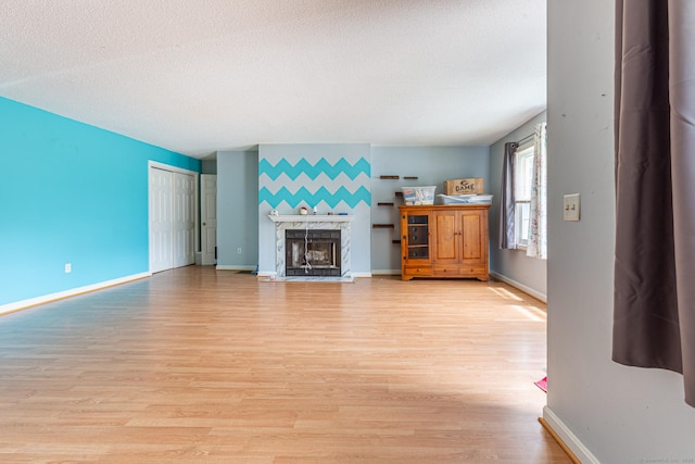 286 Laura Blvd Unit 286, Norwich, CT 06360 - unfurnished living room featuring light wood-type flooring, a premium fireplace, a textured ceiling, and an accent wall