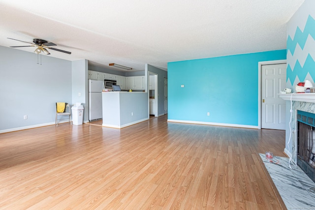 286 Laura Blvd Unit 286, Norwich, CT 06360 - unfurnished living room featuring a premium fireplace, light wood-style flooring, a ceiling fan, and a textured ceiling