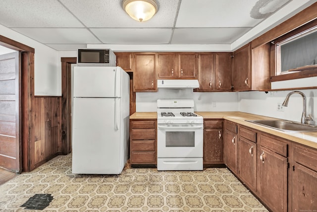 2 Scofield Pl, Norwalk, CT 06855 - kitchen with white appliances, a drop ceiling, under cabinet range hood, light countertops, and a wainscoted wall