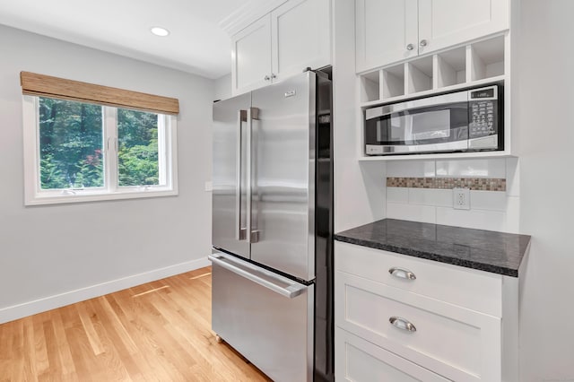 39 Clover Dr, Wilton, CT 06897 - kitchen featuring appliances with stainless steel finishes, dark stone counters, light wood-style flooring, white cabinets, and decorative backsplash