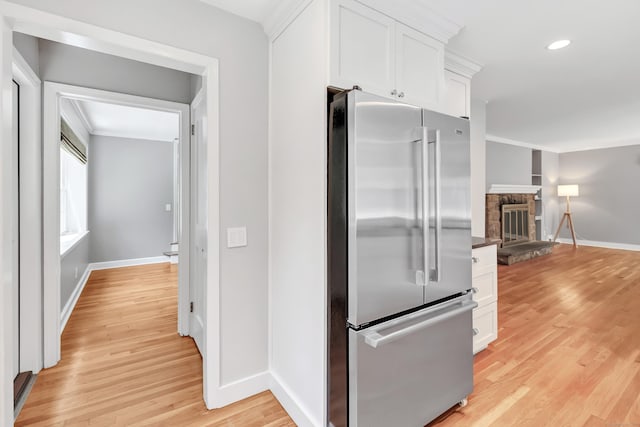 39 Clover Dr, Wilton, CT 06897 - kitchen featuring high quality fridge, white cabinets, light wood-style flooring, a fireplace, and recessed lighting
