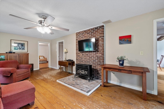853 Pole Bridge Rd, Woodstock, CT 06281 - living area with a wood stove, wood finished floors, a ceiling fan, and a textured ceiling