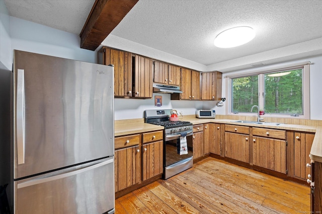 853 Pole Bridge Rd, Woodstock, CT 06281 - kitchen featuring appliances with stainless steel finishes, under cabinet range hood, brown cabinets, light wood finished floors, and a textured ceiling