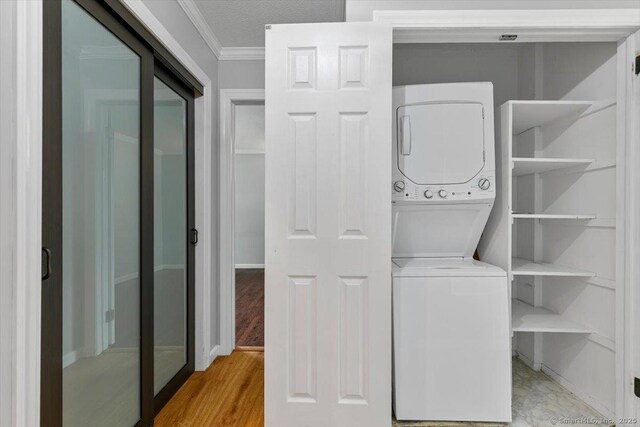 153 Marconi Ave Unit 153, Bridgeport, CT 06606 - laundry room featuring estacked washer and dryer, crown molding, and light wood-style floors