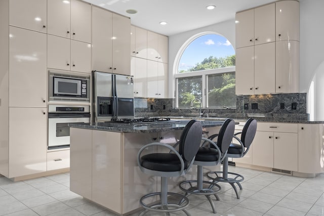 45 Brookview Ct, Groton, CT 06340 - kitchen with appliances with stainless steel finishes, dark stone counters, light tile patterned floors, a center island, and recessed lighting