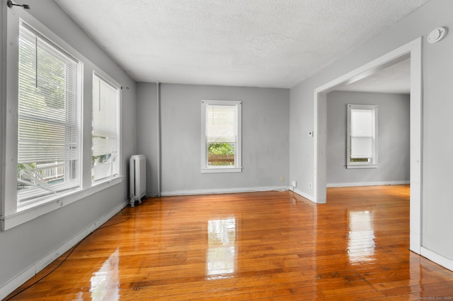 49 Freeman Ave, Norwich, CT 06360 - unfurnished room with radiator heating unit, a smoke detector, a textured ceiling, and light wood-type flooring