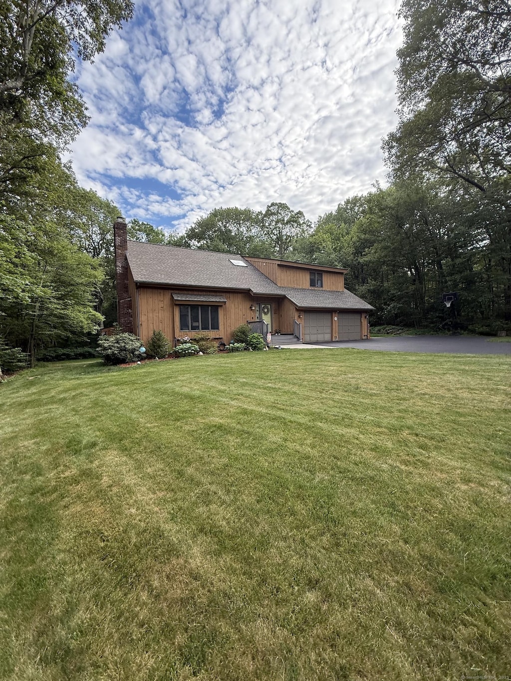681 Willis St, Bristol, CT 06010 - view of front of home with a chimney, asphalt driveway, an attached garage, and a front yard