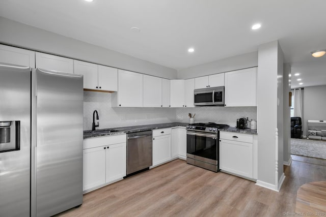 121 Russo Ave Unit 11, East Haven, CT 06513 - kitchen featuring stainless steel appliances, light wood-style flooring, white cabinetry, decorative backsplash, and dark stone counters