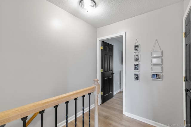 121 Russo Ave Unit 11, East Haven, CT 06513 - hallway featuring light wood-style floors, a textured ceiling, and an upstairs landing