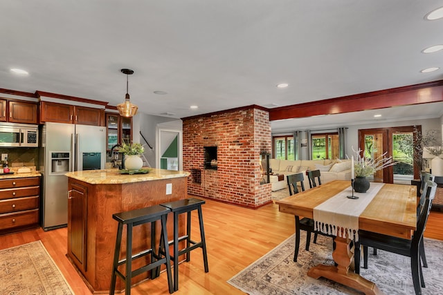 24 Buttonball Ln, Glastonbury, CT 06033 - kitchen with stainless steel appliances, a center island, light wood-type flooring, crown molding, and decorative light fixtures