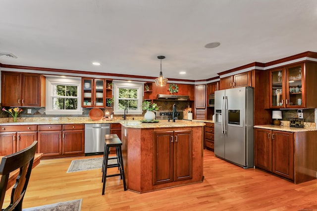 24 Buttonball Ln, Glastonbury, CT 06033 - kitchen featuring stainless steel appliances, decorative backsplash, light wood finished floors, under cabinet range hood, and glass insert cabinets